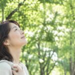 街路樹の下で木を見上げる女性