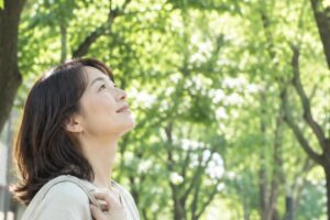 街路樹の下で木を見上げる女性