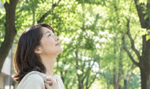 街路樹の下で木を見上げる女性