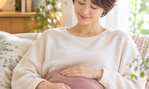ソファで温かいクッションをお腹に当て、ほっとする女性
