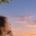 夕暮れの西の空に浮かぶ三日月を見上げる女性