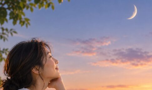 夕暮れの西の空に浮かぶ三日月を見上げる女性
